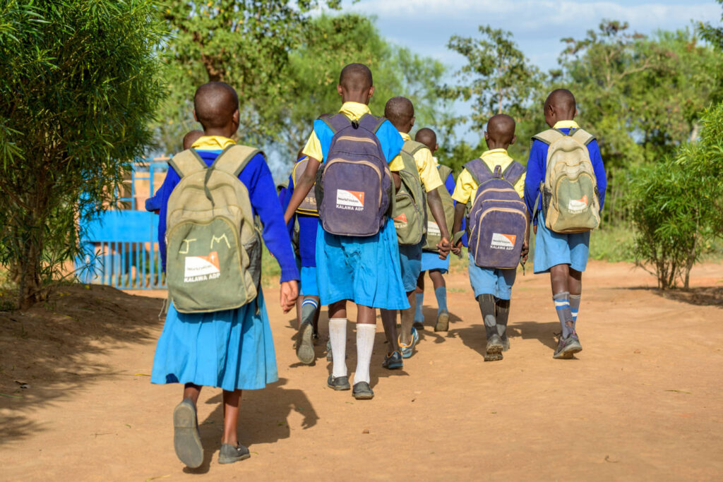 School children head home after class, wearing their World Vision backpacks, at  Itumbule Primary School in Kalawa ADP, Kenya.

There are 65 children in the Itumbule Primary Bible Club—26 of whom are sponsored. The students sing, learn Bible verses, hear the word of God, and plant and care for fruit trees. The Bible club is part of World Vision’s Transformed Church for Transformed Communities program. There are 40 such Bible clubs in the primary schools in Kalawa. The classes are taught by Catherine Mutinda, Philomenah Lukas, and Mirriam Musyim. Standout members of the class are Mumo Musango, the school president; Nyamai Kaliwa, who wants to be a pilot someday as he loves the thought of travel; Minoo Mukuni, who wants to be an attorney; and Mulheu Mulhui, who has grown spiritually because of the club. The children learn Bible verses, great songs about Jesus, and are encouraged to grow in faith and good character.