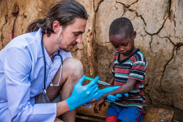 Male doctor is doing an injection to little African boy in small Masai village, Southern Kenya. Maasai tribe inhabiting southern Kenya and northern Tanzania, and they are related to the Samburu.